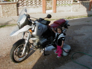 Mi hija Queralt ayudandome a limpiar la moto.