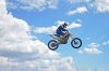 35964328-Jinete-del-motocr-s-de-pie-sobre-la-moto-MX-est-volando-sobre-la-colina-sobre-un-fondo-.jpg