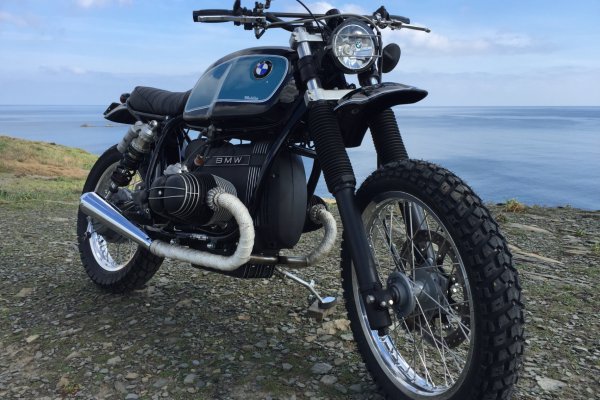 La scrambler frente al mar, con neumáticos de tacos y manillar ancho